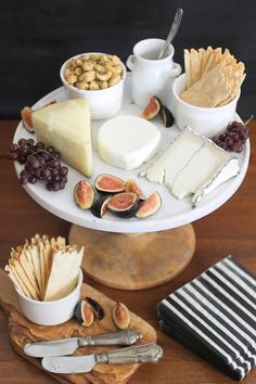 an assortment of cheeses, crackers and figurines on a cake plate