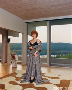 a woman standing in front of a large window wearing a black and white checkered dress