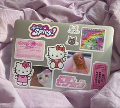 a laptop with hello kitty stickers on it sitting on a pink bed sheet covered in sheets