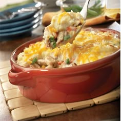 a red casserole dish filled with chicken and vegetables