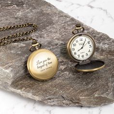 two pocket watches sitting on top of a rock