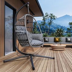 a hanging chair on a wooden deck with mountains in the background