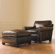 a brown leather chair and ottoman in an empty room