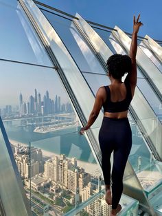 a woman standing on top of a tall building looking out at the city from an observation platform