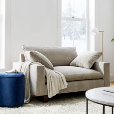 a living room with a couch, coffee table and ottoman in front of a window