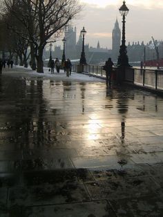 people are walking down the sidewalk on a rainy day