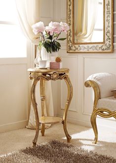 a small table with flowers on it in front of a mirror and a white chair