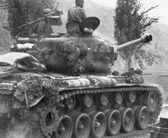 an old tank with two men sitting on it's top and another man standing next to it