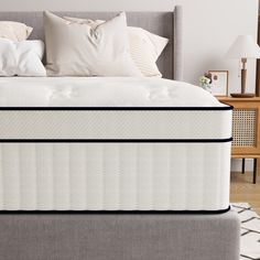 a bed with two pillows on top of it next to a night stand and nightstand