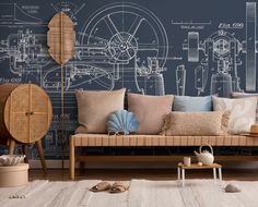 a couch and some pillows in front of a wall with blueprints on it