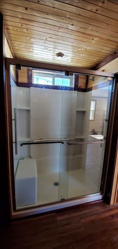 a bathroom with a glass shower door and wooden ceiling