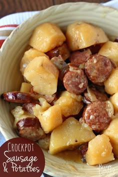 a bowl filled with sausage and pineapples on top of a wooden tablecloth