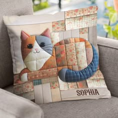 a cat pillow sitting on top of a couch next to a window with the name sophha