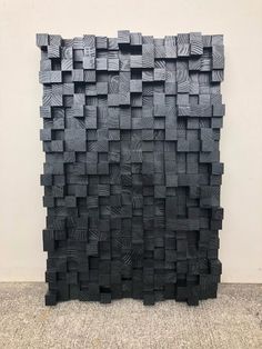 a sculpture made out of wooden blocks on the floor in front of a white wall