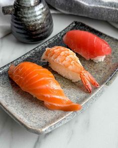 two pieces of sushi sit on a plate next to a salt and pepper shaker