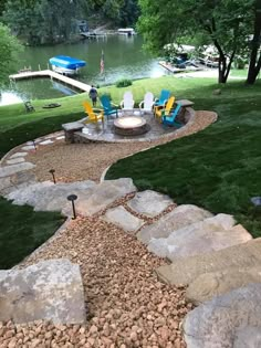 there is a fire pit in the middle of this yard with lawn chairs and rocks around it