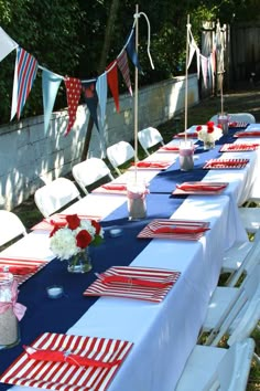 a long table set up with red, white and blue place settings for an outdoor party