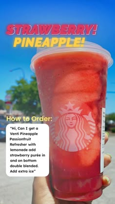 a person holding up a drink with the words strawberry pineapple written on it in front of them