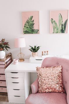 a pink chair sitting in front of a white desk with two paintings on the wall