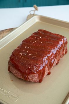 a piece of meat covered in ketchup on a tray