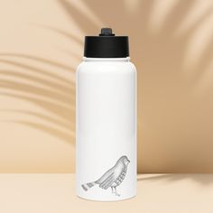 a white water bottle with a bird drawn on the side and a black lid sitting on a table