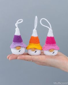 three small crocheted gnomes sitting on top of each other in their hands