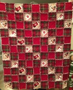 a red and white quilt hanging on the side of a wall next to a teddy bear