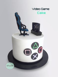 a white cake with black and blue decorations on it's top, sitting in front of a computer chair