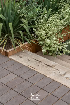 two wooden planters sitting next to each other on top of a brick floor covered in plants