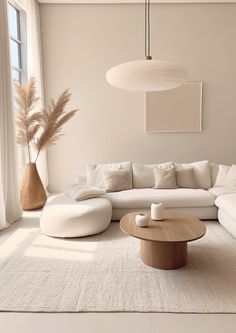 a living room with a large white couch and round coffee table in front of a window