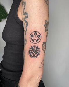 a woman with a tattoo on her arm has a flower and two circles in the middle