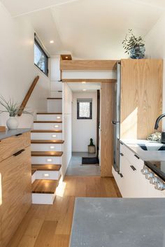 a kitchen with wooden floors and white walls next to a staircase leading up to the second floor