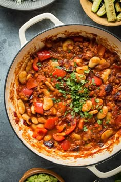 a pot filled with beans and vegetables on top of a table next to other dishes