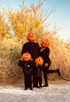 three people with pumpkins on their heads