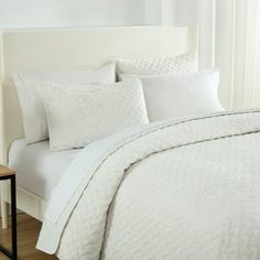 a bed with white sheets and pillows in a room