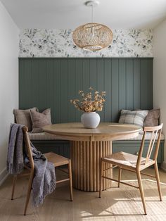 a dining room table with chairs and a bench in front of green paneled walls