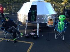 a man sitting in a chair next to an alien tent and two chairs with decorations on them