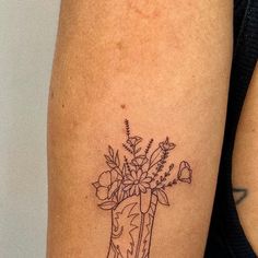 a woman's arm with a tattoo on it that has flowers in a boot