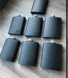 six black flasks sitting on top of a wooden table