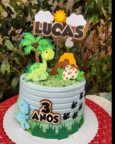 a birthday cake decorated with dinosaurs and trees