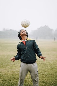 a man is playing with a soccer ball on his head in the grass while wearing sweatpants