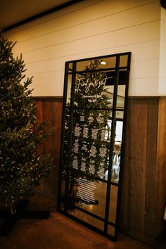 a christmas tree sitting in front of a glass door with the names of people on it