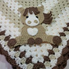 a crocheted teddy bear laying on top of a blanket