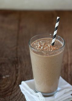 a smoothie in a glass with a black and white striped straw is sitting on a napkin