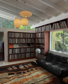 a living room filled with lots of books on top of a hard wood book shelf