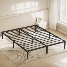 a metal bed frame sitting on top of a white rug next to a large window