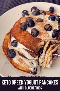 pancakes with blueberries and whipped cream are stacked on top of each other, ready to be eaten