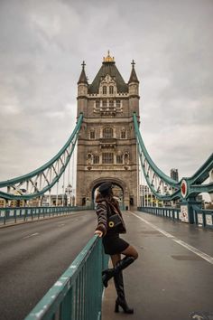 a woman standing on the side of a bridge