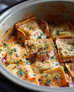 a casserole dish with cheese and parsley in a white crock pot