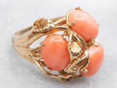 Add a touch of whimsy and nature to your outfit with this vintage gold botanical ring. The oval cut coral adds a pop of color and the cocktail ring design makes a playful statement. A fun and unique addition to any jewelry collection! Metal: 14K Yellow Gold Gem: 3 Coral Gem Measurements: 6.8 x 9.3 mm, Oval Ring Size: 6.75 Marks: "14K {S}" Stamped on the inside band SKU #: A48950 Each piece has been identified and graded by a Graduate Gemologist who has been certified by the Gemological Institute of America (GIA). We have six brick-and-mortar storefronts in Maine, Massachusetts, and New Hampshire and have been in business for over 25 years! Please visit our Shop's About Page or our website for more information about our jewelry. For questions about diamond grading, we recommend the  Gemolog Orange Multi-stone Ring, Luxury Elegant Coral Rings, Cocktail Ring Designs, Luxury Coral Gemstone Ring, Adjustable Hand-strung Coral Jewelry, Hand-strung Red Coral Jewelry, Botanical Ring, Coral Ring, Oval Ring